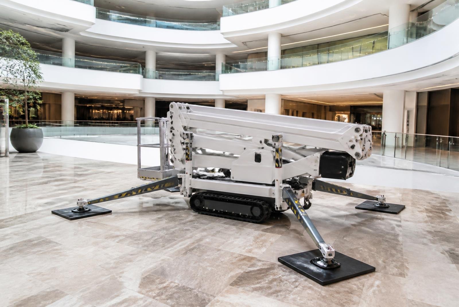 Compact tracked spider lift on non-marking tracks and outrigger pads inside a shopping mall atrium